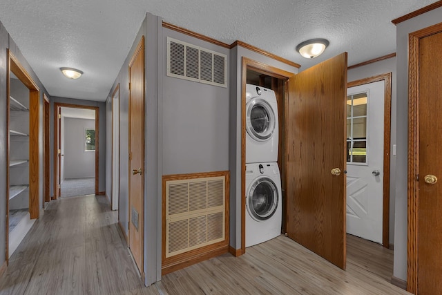9353 Ideal Rd, Watab Twp, MN 56367 - laundry area featuring stacked washer and clothes dryer, a textured ceiling, light wood-style flooring, and ornamental molding