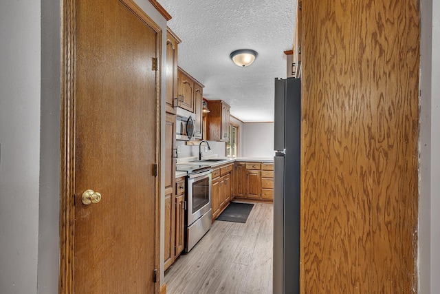 9353 Ideal Rd, Watab Twp, MN 56367 - kitchen featuring appliances with stainless steel finishes, light wood-type flooring, light countertops, a textured ceiling, and brown cabinetry