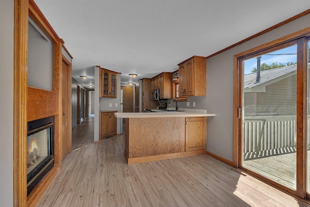9353 Ideal Rd, Watab Twp, MN 56367 - kitchen with light wood finished floors, light countertops, a peninsula, brown cabinets, and glass insert cabinets