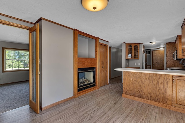 9353 Ideal Rd, Watab Twp, MN 56367 - kitchen featuring glass insert cabinets, light wood-style floors, a textured ceiling, a peninsula, and freestanding refrigerator