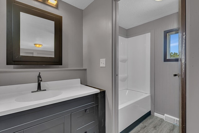 9353 Ideal Rd, Watab Twp, MN 56367 - full bathroom featuring vanity, wood finished floors, a textured ceiling, and washtub / shower combination