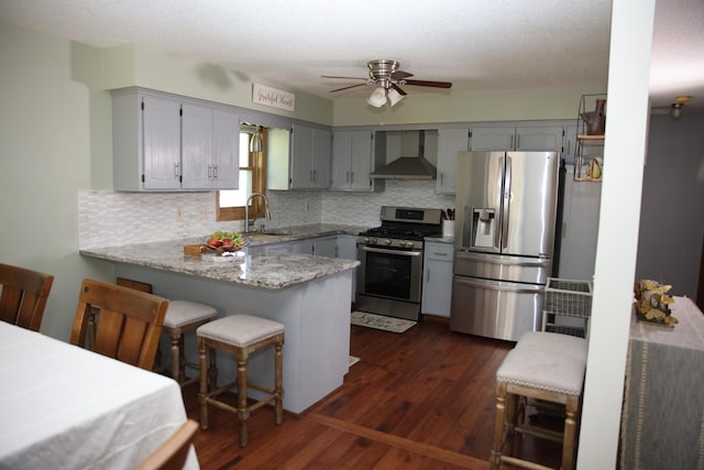 3930 99th Ave NE, Blaine, MN 55014 - kitchen featuring appliances with stainless steel finishes, wall chimney range hood, a peninsula, tasteful backsplash, and a textured ceiling