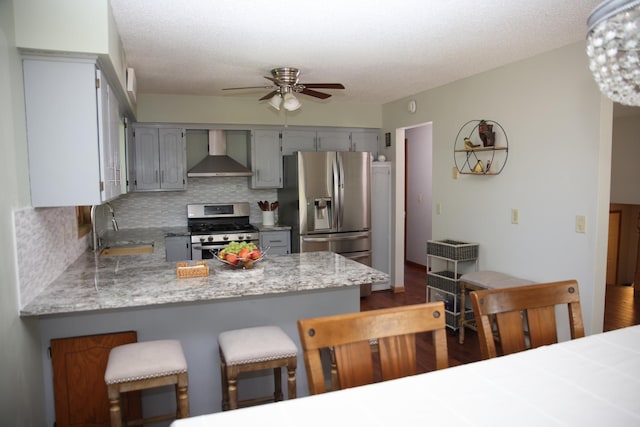 3930 99th Ave NE, Blaine, MN 55014 - kitchen featuring appliances with stainless steel finishes, wall chimney range hood, gray cabinets, a ceiling fan, and a textured ceiling