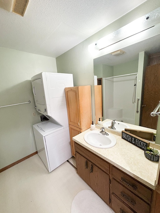 428 16th St, Windom, MN 56101 - bathroom with stacked washer / dryer, vanity, a shower, a textured ceiling, and tile patterned floors