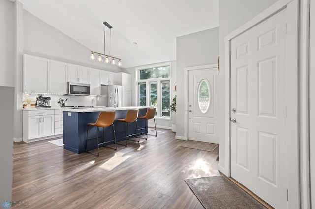 3501 19th St S, Fargo, ND 58104 - kitchen featuring stainless steel appliances, decorative backsplash, white cabinets, a breakfast bar area, and dark wood-style flooring