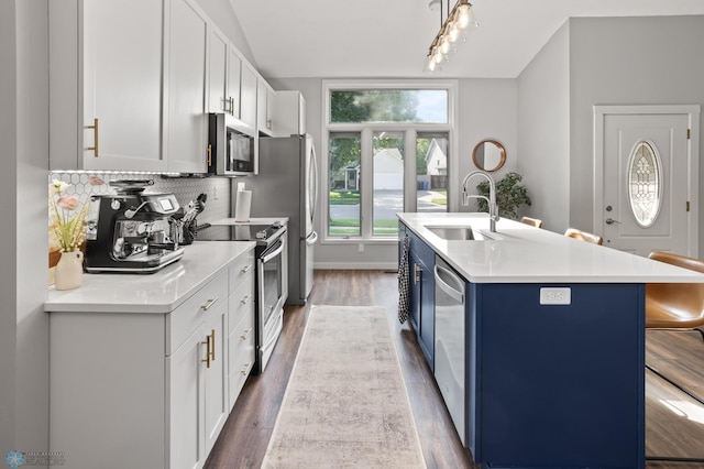 3501 19th St S, Fargo, ND 58104 - kitchen with stainless steel appliances, blue cabinetry, a center island with sink, decorative backsplash, and white cabinetry