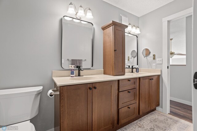 3501 19th St S, Fargo, ND 58104 - bathroom with double vanity, ceiling fan, wood finished floors, and a textured ceiling