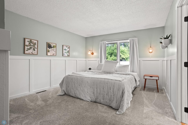3501 19th St S, Fargo, ND 58104 - bedroom featuring a decorative wall, a wainscoted wall, a textured ceiling, and carpet