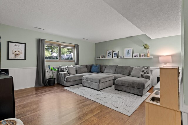 3501 19th St S, Fargo, ND 58104 - living area featuring light wood-style flooring, a textured ceiling, and a wainscoted wall