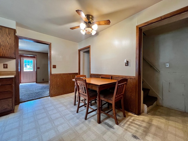 290 5th Ave, Granite Falls, MN 56241 - dining space with a wainscoted wall, a ceiling fan, stairway, light floors, and wooden walls