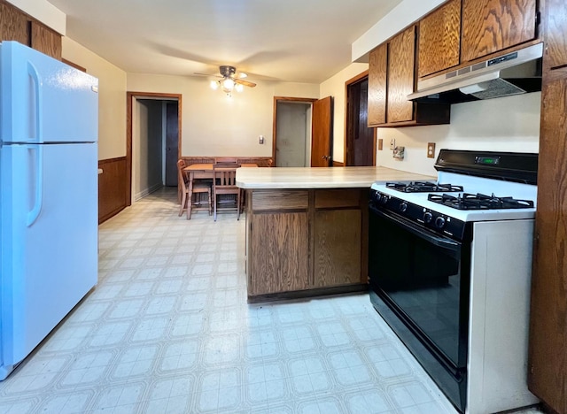 290 5th Ave, Granite Falls, MN 56241 - kitchen featuring gas stove, freestanding refrigerator, under cabinet range hood, light floors, and a peninsula
