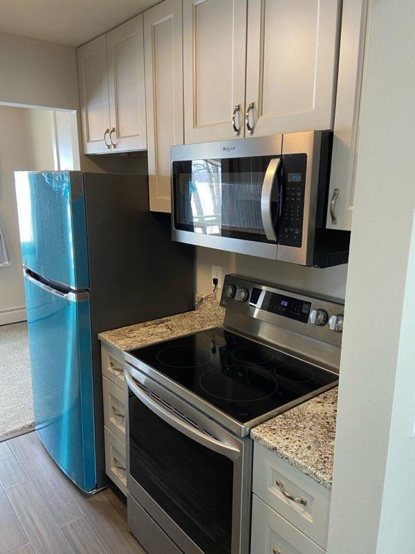 4363 Wilshire Blvd Unit 302, Mound, MN 55364 - kitchen featuring stainless steel appliances, wood finished floors, white cabinetry, and light stone counters