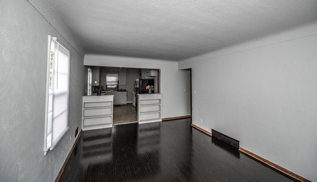1194 Forest St, Saint Paul, MN 55106 - unfurnished living room with a textured ceiling and dark wood finished floors
