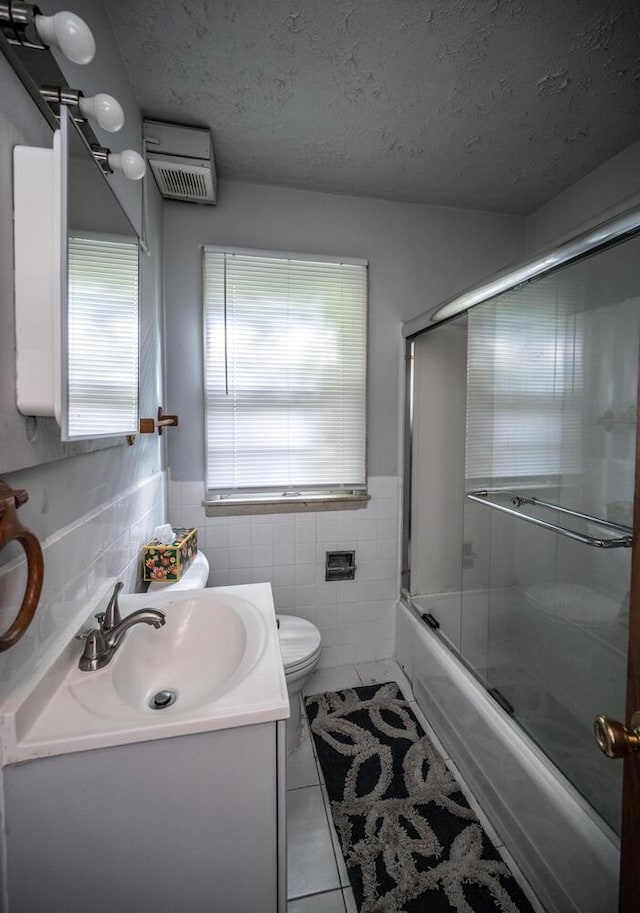 1194 Forest St, Saint Paul, MN 55106 - bathroom featuring tile walls, tile patterned flooring, vanity, shower / bath combination with glass door, and a textured ceiling
