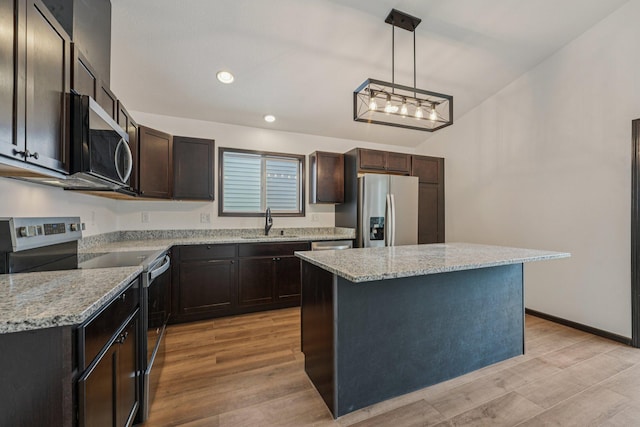 1002 Conway St, Saint Paul, MN 55106 - kitchen with stainless steel appliances, light stone counters, light wood-style floors, a kitchen island, and decorative light fixtures