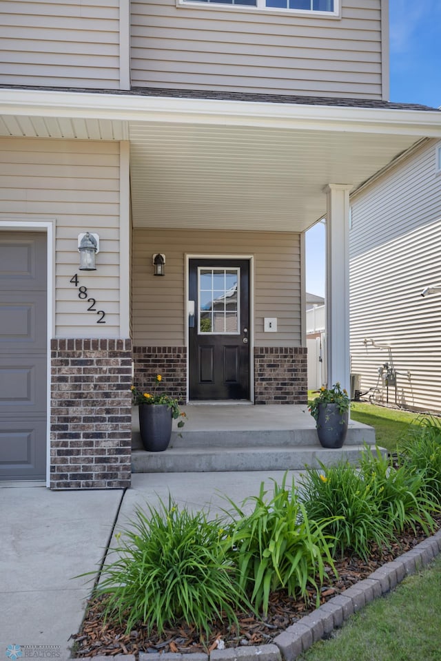 4822 34th Ave S, Fargo, ND 58104 - property entrance with a porch, brick siding, and a garage