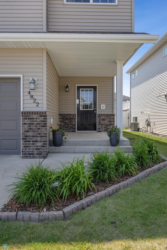 4822 34th Ave S, Fargo, ND 58104 - doorway to property with brick siding, covered porch, and a garage