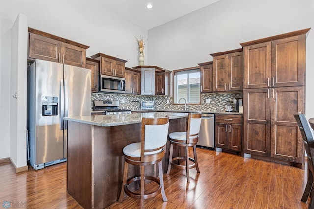 4822 34th Ave S, Fargo, ND 58104 - kitchen featuring appliances with stainless steel finishes, a kitchen island, dark wood-style floors, decorative backsplash, and a breakfast bar area