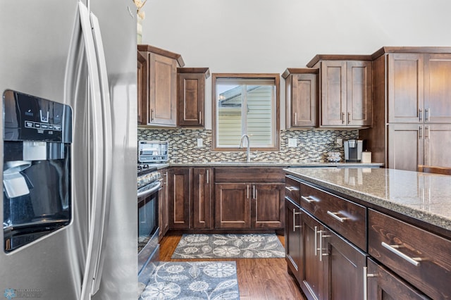 4822 34th Ave S, Fargo, ND 58104 - kitchen with stainless steel appliances, light stone counters, tasteful backsplash, and wood finished floors
