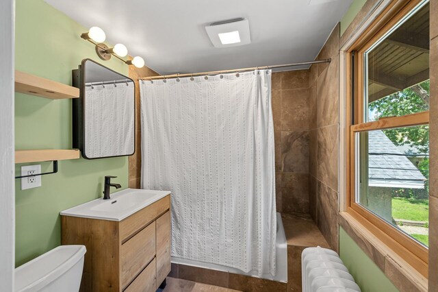 3841 Columbus Ave, Minneapolis, MN 55407 - bathroom featuring radiator, vanity, plenty of natural light, and a shower with shower curtain