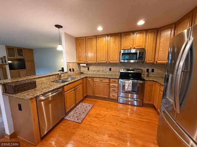 2052 Wilhelm Ct, Shakopee, MN 55379 - kitchen with stainless steel appliances, light wood finished floors, light stone counters, tasteful backsplash, and pendant lighting