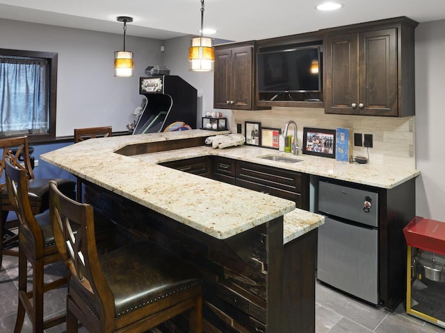 2052 Wilhelm Ct, Shakopee, MN 55379 - kitchen with dark brown cabinets, a breakfast bar area, a peninsula, light stone counters, and recessed lighting