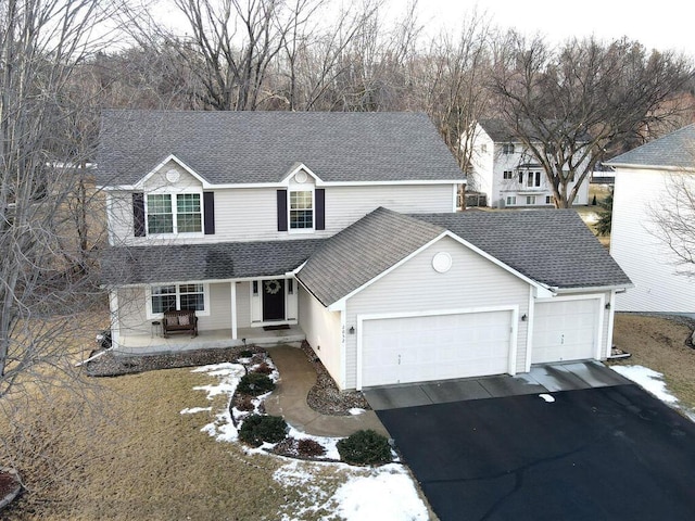 2052 Wilhelm Ct, Shakopee, MN 55379 - traditional home with driveway, an attached garage, a shingled roof, and covered porch