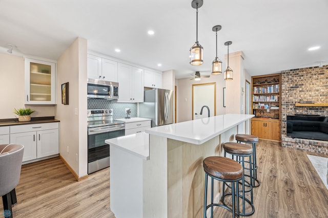 2636 18th St S Unit 8, Fargo, ND 58103 - kitchen with stainless steel appliances, light wood finished floors, a fireplace, a kitchen breakfast bar, and recessed lighting