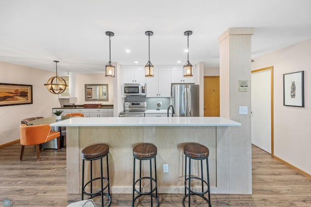 2636 18th St S Unit 8, Fargo, ND 58103 - kitchen featuring stainless steel appliances, a kitchen bar, light wood finished floors, white cabinets, and tasteful backsplash
