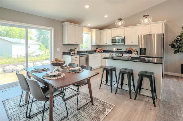 6006 Fuller Cir, Wyoming, MN 55092 - kitchen with appliances with stainless steel finishes, dark countertops, white cabinetry, lofted ceiling, and a breakfast bar