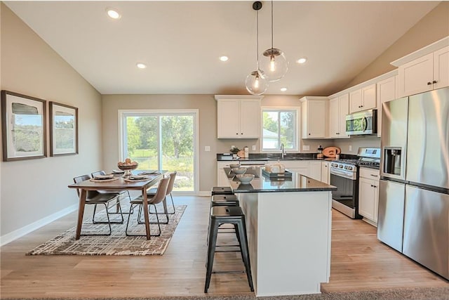 6006 Fuller Cir, Wyoming, MN 55092 - kitchen with stainless steel appliances, lofted ceiling, dark countertops, a kitchen island, and white cabinets