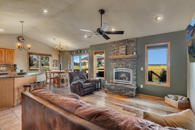 511 8th St SW, Rice, MN 56367 - living area with a chandelier, lofted ceiling, a stone fireplace, ceiling fan, and a textured ceiling