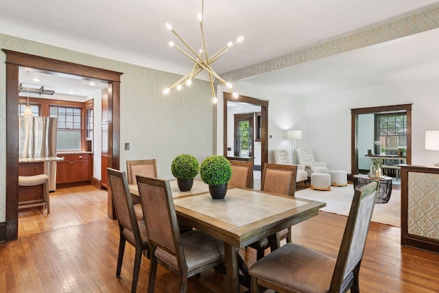 1088 Lincoln Ave, Saint Paul, MN 55105 - dining space with light wood finished floors, a chandelier, wallpapered walls, and an accent wall