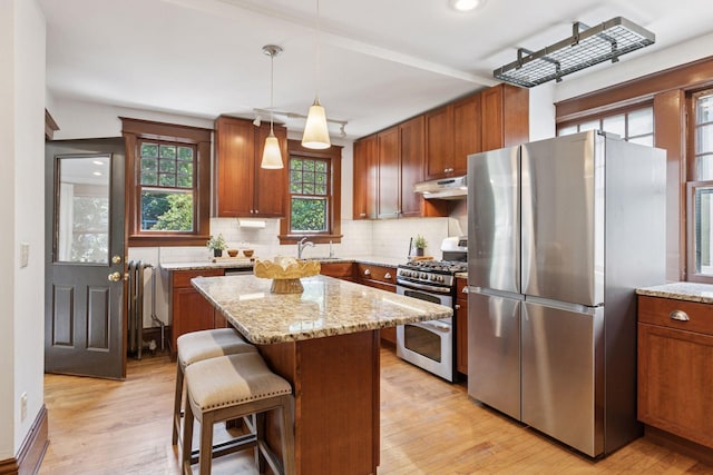1088 Lincoln Ave, Saint Paul, MN 55105 - kitchen featuring appliances with stainless steel finishes, under cabinet range hood, light wood finished floors, tasteful backsplash, and light stone counters