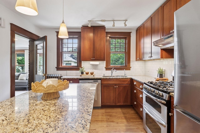 1088 Lincoln Ave, Saint Paul, MN 55105 - kitchen with appliances with stainless steel finishes, under cabinet range hood, light wood-type flooring, backsplash, and light stone countertops