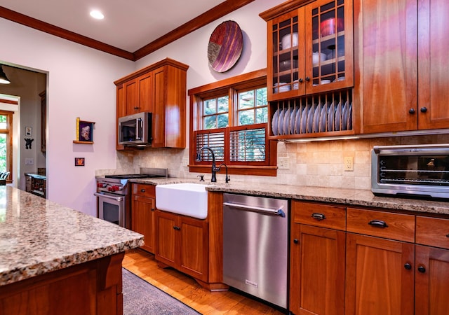582 Summit Ave, Saint Paul, MN 55102 - kitchen with stainless steel appliances, brown cabinets, light wood-style floors, tasteful backsplash, and ornamental molding