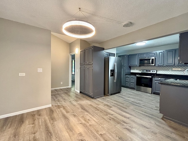 1414 Danube Rd, Fridley, MN 55432 - kitchen with stainless steel appliances, dark countertops, light wood-style floors, backsplash, and lofted ceiling