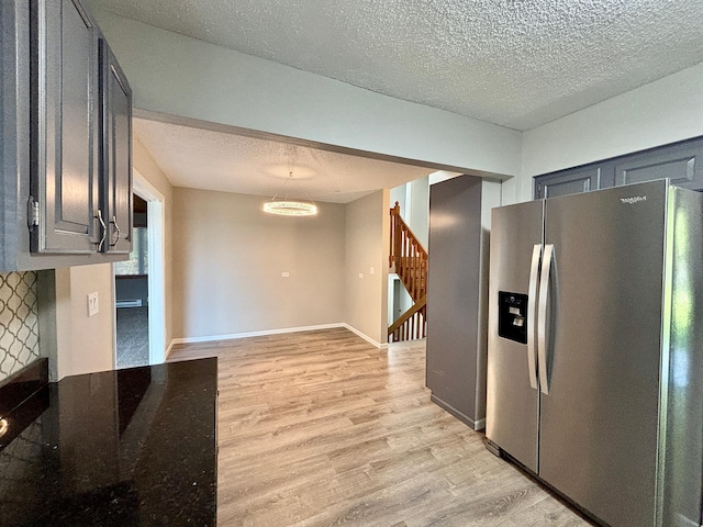 1414 Danube Rd, Fridley, MN 55432 - kitchen with stainless steel fridge, light wood finished floors, a textured ceiling, and dark stone countertops