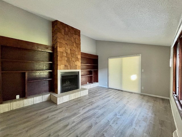 1414 Danube Rd, Fridley, MN 55432 - unfurnished living room featuring lofted ceiling, a fireplace, a textured ceiling, wood finished floors, and built in features