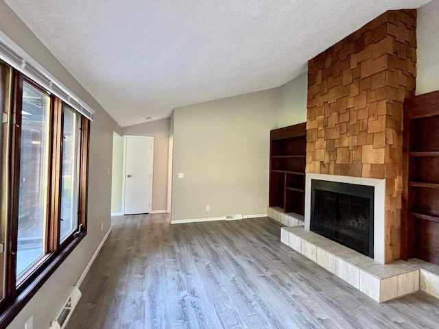 1414 Danube Rd, Fridley, MN 55432 - unfurnished living room featuring a textured ceiling, wood finished floors, a tiled fireplace, and lofted ceiling