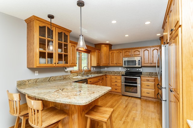 2944 Mayowood Common Cir SW, Rochester, MN 55902 - kitchen with stainless steel appliances, a peninsula, recessed lighting, a kitchen breakfast bar, and glass insert cabinets