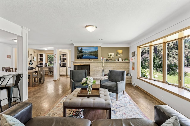 1281 Minnehaha Pkwy, Minneapolis, MN 55419 - living area featuring wood finished floors, a brick fireplace, a textured ceiling, and decorative columns