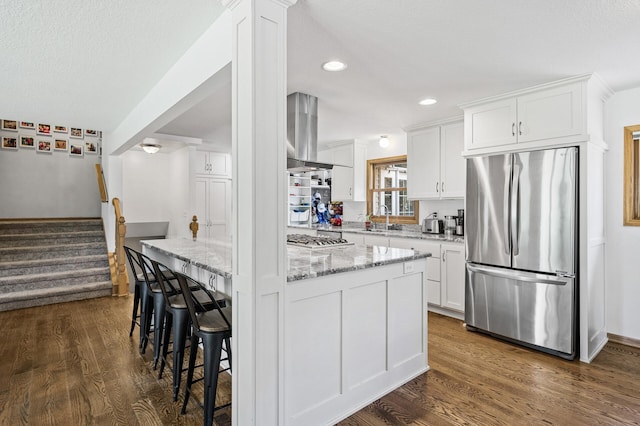 1281 Minnehaha Pkwy, Minneapolis, MN 55419 - kitchen featuring appliances with stainless steel finishes, wall chimney range hood, light stone countertops, white cabinetry, and recessed lighting