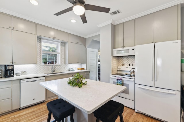 4356 Nokomis Ave, Minneapolis, MN 55406 - kitchen with white appliances, crown molding, gray cabinets, a breakfast bar area, and light wood-style floors