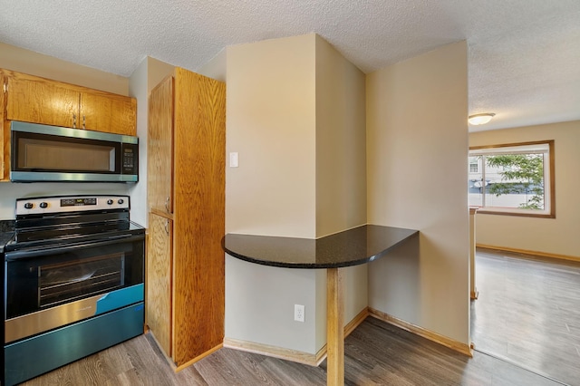 960 Burr St, Saint Paul, MN 55130 - kitchen with appliances with stainless steel finishes, wood finished floors, a textured ceiling, and dark countertops