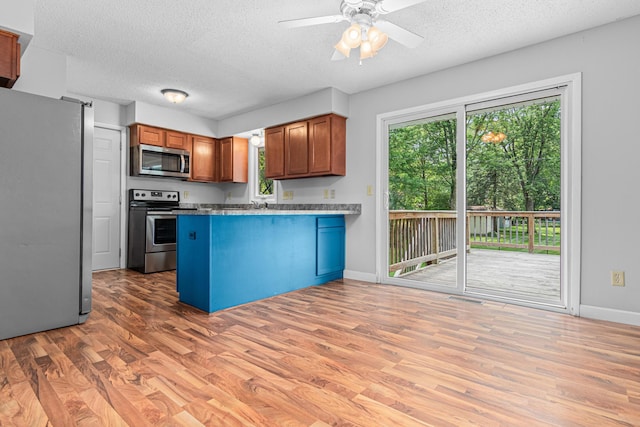 8210 Red Oak Dr, Mounds View, MN 55112 - kitchen with stainless steel appliances, a peninsula, a textured ceiling, light wood-style flooring, and plenty of natural light