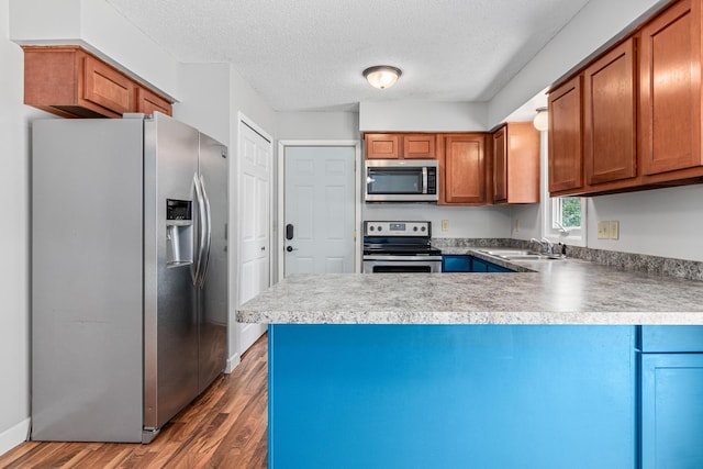 8210 Red Oak Dr, Mounds View, MN 55112 - kitchen featuring appliances with stainless steel finishes, a peninsula, wood finished floors, a textured ceiling, and brown cabinetry