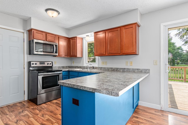 8210 Red Oak Dr, Mounds View, MN 55112 - kitchen with appliances with stainless steel finishes, a peninsula, a kitchen bar, wood finished floors, and a textured ceiling