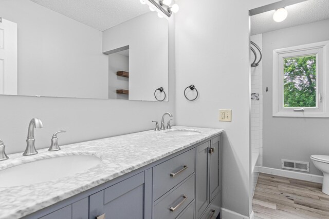 8210 Red Oak Dr, Mounds View, MN 55112 - bathroom with a textured ceiling, double vanity, wood finished floors, and shower / tub combination