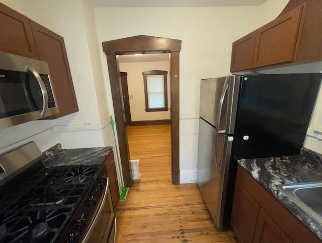 3815 Dupont Ave N, Minneapolis, MN 55412 - kitchen with appliances with stainless steel finishes, light wood-style floors, and dark stone counters